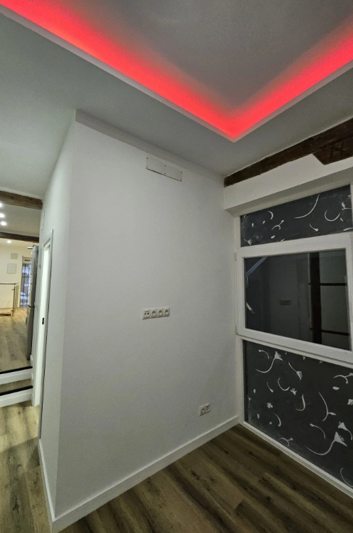 Habitación moderna con luz roja en techo y paredes blancas